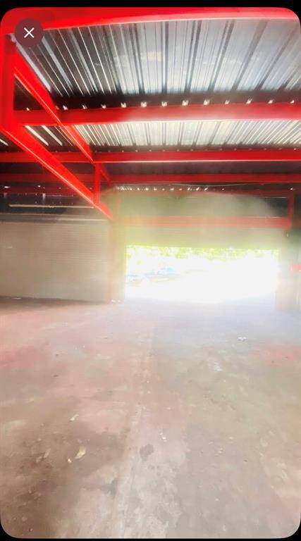Spacious industrial garage with striking red steel beams and a large open doorway for abundant natural light and easy access.