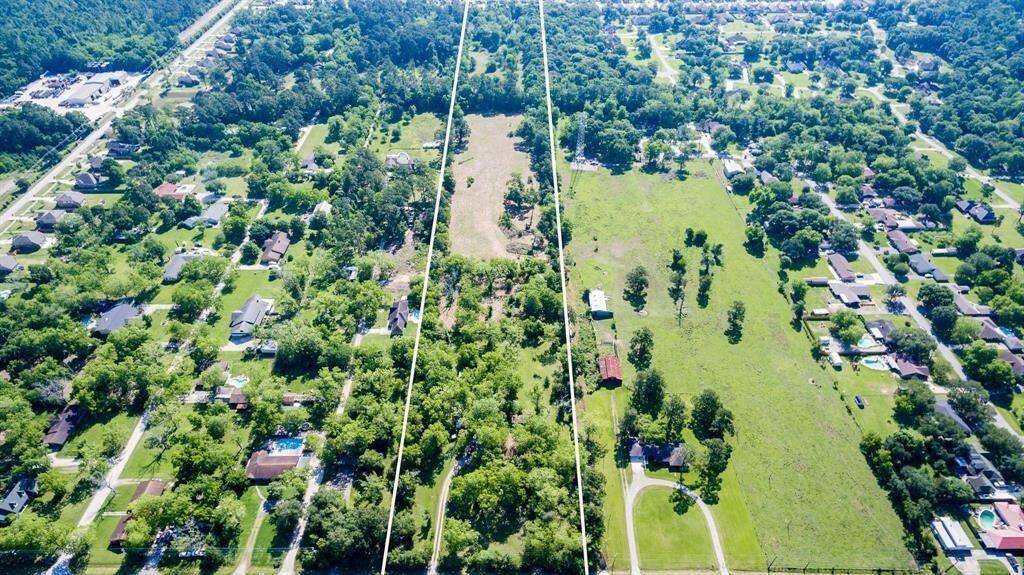 This aerial photo shows a large, expansive property outlined in white, featuring a mixture of open grassy areas and clusters of trees, offering both open space and natural privacy. The land is primarily flat and provides a rural setting with clear skies and a distant view of a city skyline, indicating proximity to urban amenities.