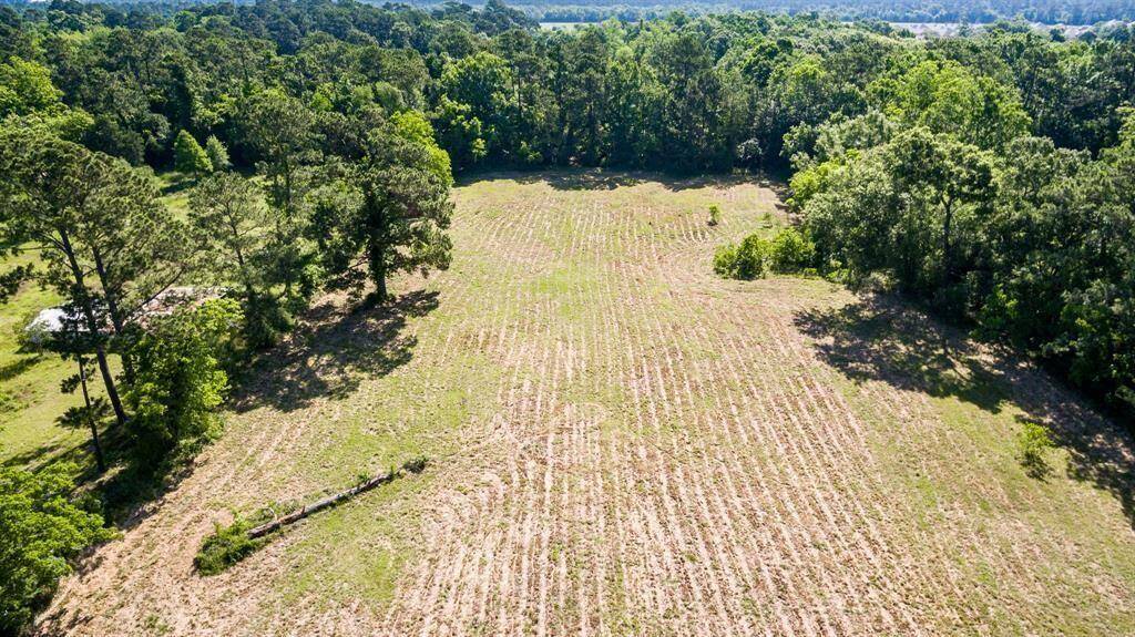 This aerial photo showcases a spacious, open plot of land with a mix of cleared areas and surrounding trees, offering a potential site for building a home with natural privacy.