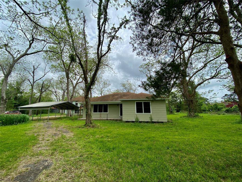 Charming single-story home in a lush, green setting with mature trees and a spacious yard. Features a carport and traditional exterior.