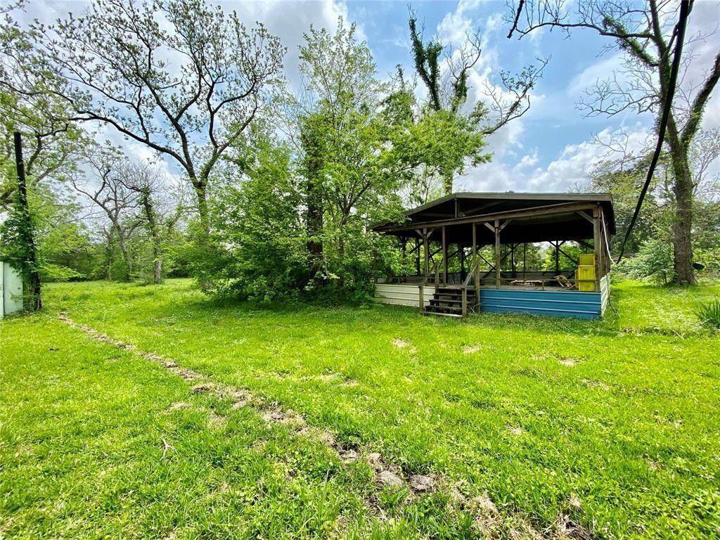 This is a lush, green property featuring a simple, covered outdoor structure amidst mature trees, offering a serene, natural setting.