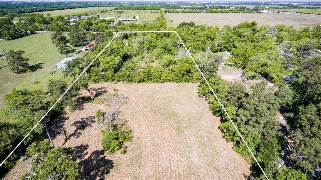 A large, rectangular plot of land, partially cleared with a mix of open fields and wooded areas, offering a blend of natural privacy and space for development. The property is outlined, indicating the boundaries of the lot.