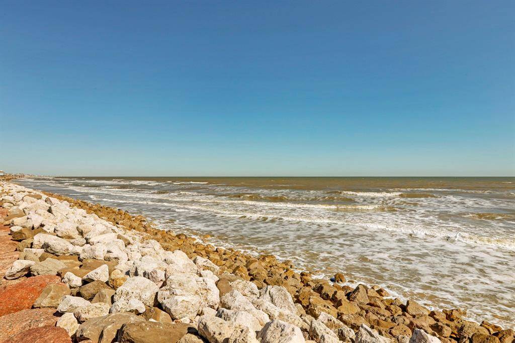 This photo showcases a scenic coastal view with a rocky shoreline and gentle waves under a clear blue sky, perfect for buyers seeking a serene waterfront location.