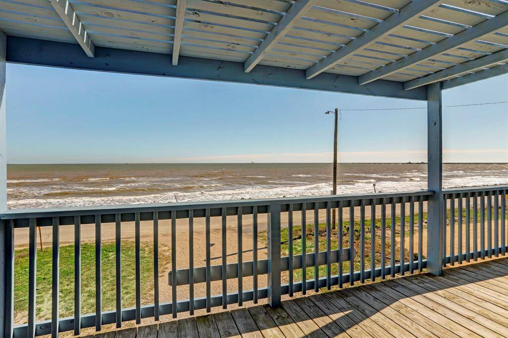 This photo showcases a beachfront view from a covered wooden deck, offering a picturesque scene of the ocean and sandy shoreline. Ideal for those seeking a serene coastal retreat.
