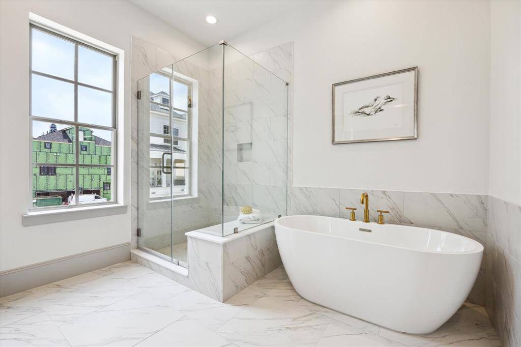 Walk-in shower with seat, porcelain tile, marble tile floors, and brass hardware.