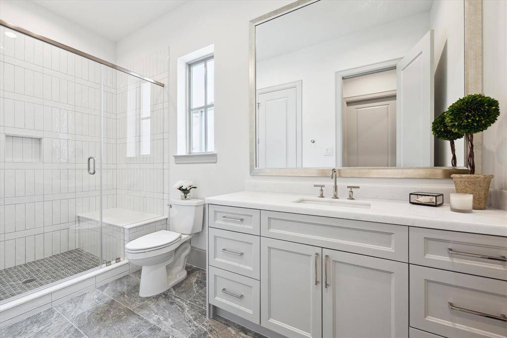 Full bath off secondary features glass enclosed shower with seat and Opal White Polished Marble countertops.