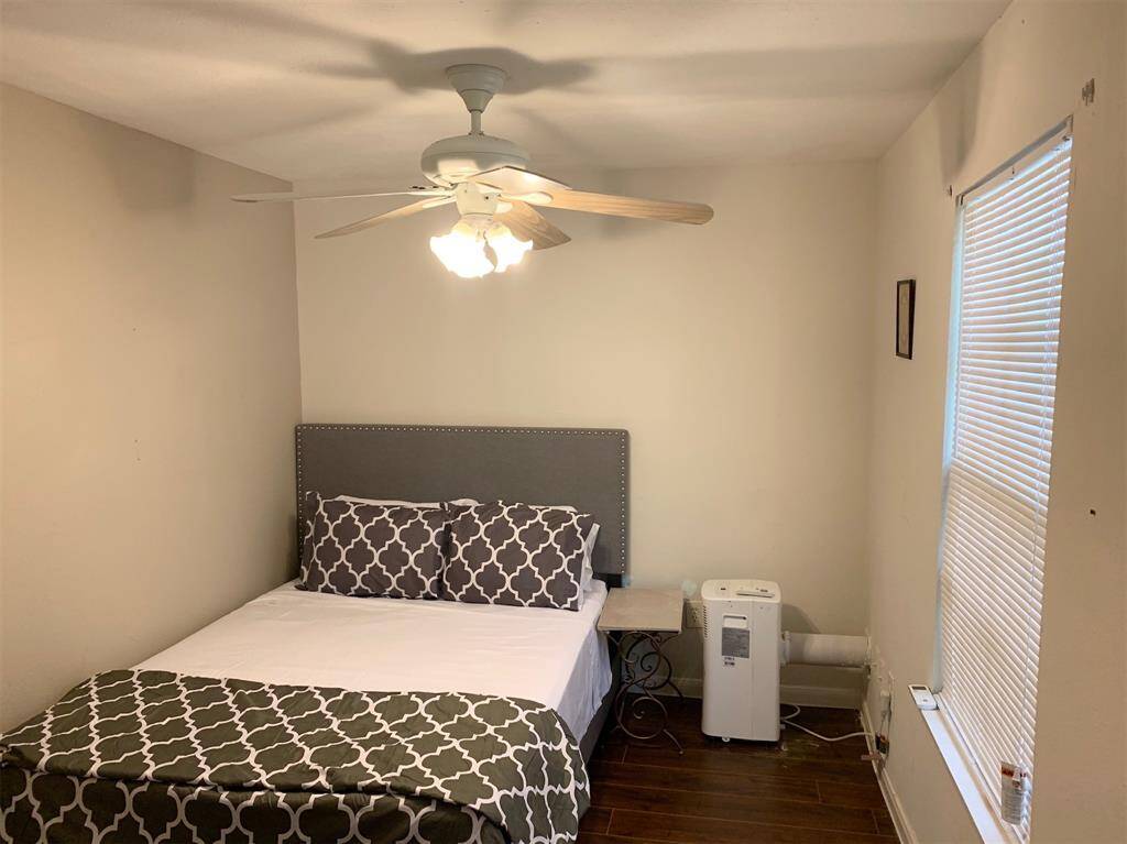 Spacious bedroom with a comfortable queen-sized bed, highlighted by a modern ceiling fan and ample natural light.