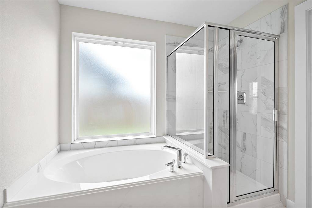 This additional view of the primary bath showcases the walk-in shower with tile surround and separate garden tub perfect for soaking after a long day.