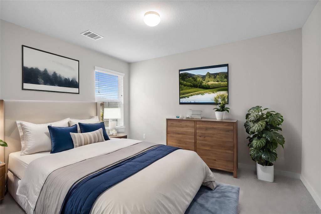 Secondary bedroom features plush carpet, custom paint and a large window with privacy blinds.