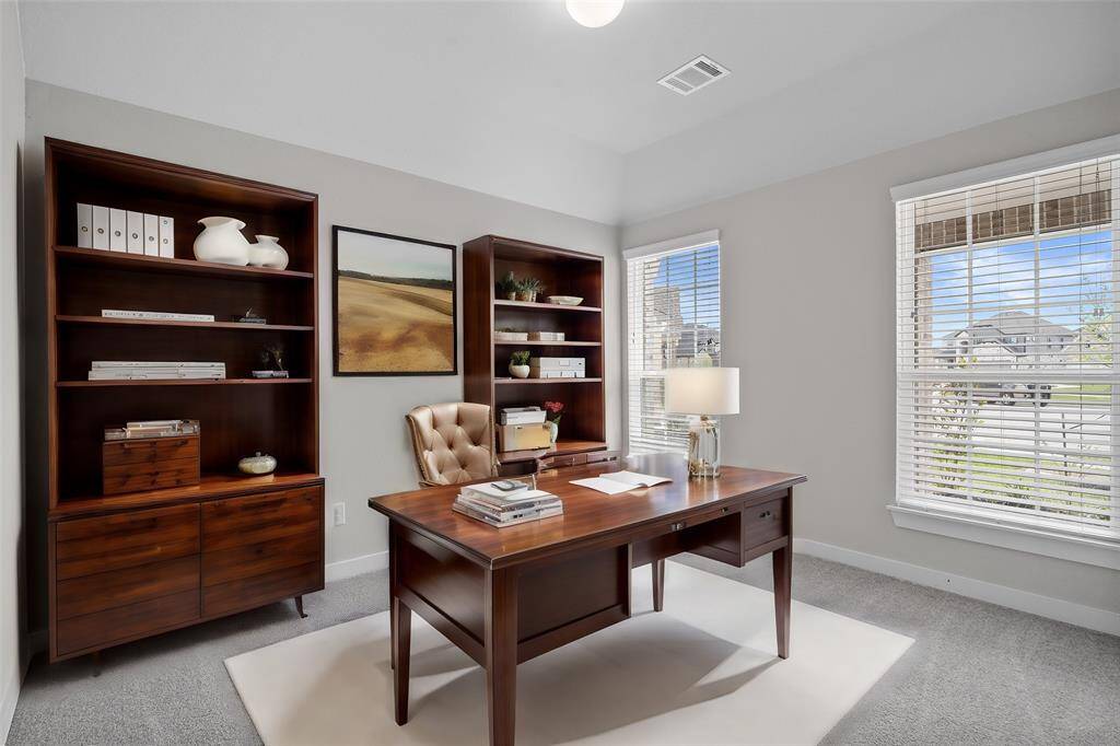 Quietly nestled in front of the home is the handsome home office. Featuring plush carpet, high ceilings, large windows with privacy blinds and custom paint.