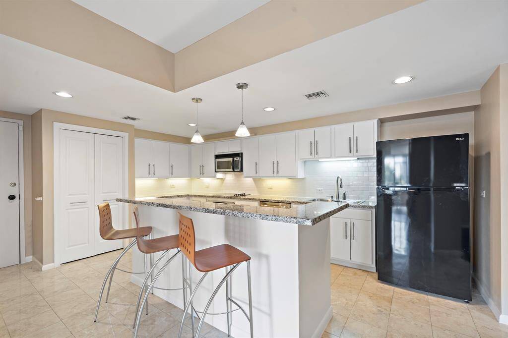 Find abundant storage options in this light and bright kitchen, featuring multiple sleek white cabinetry and a generously sized pantry.