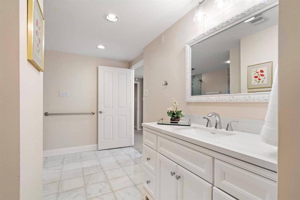 The primary bathroom showcases a large vanity area equipped with spacious counters, sconce lighting, multiple built-ins, and plumbed to accommodate an extra sink.