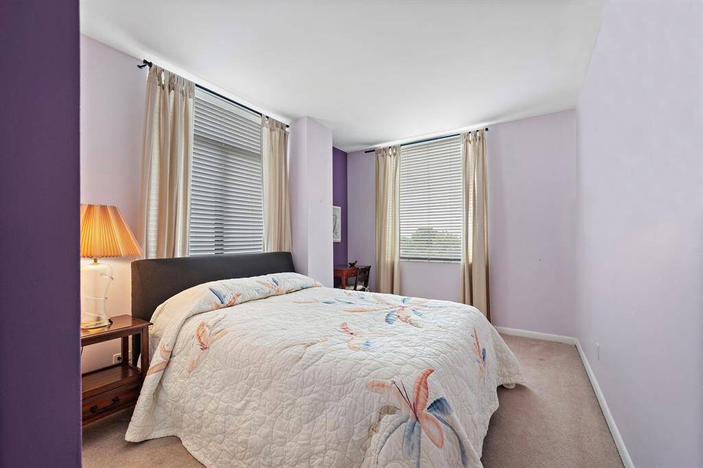 Ideal for a guest suite, this 10' x 14' corner bedroom boasts carpet flooring, tall windows, and ample space for a queen bed and a desk area.