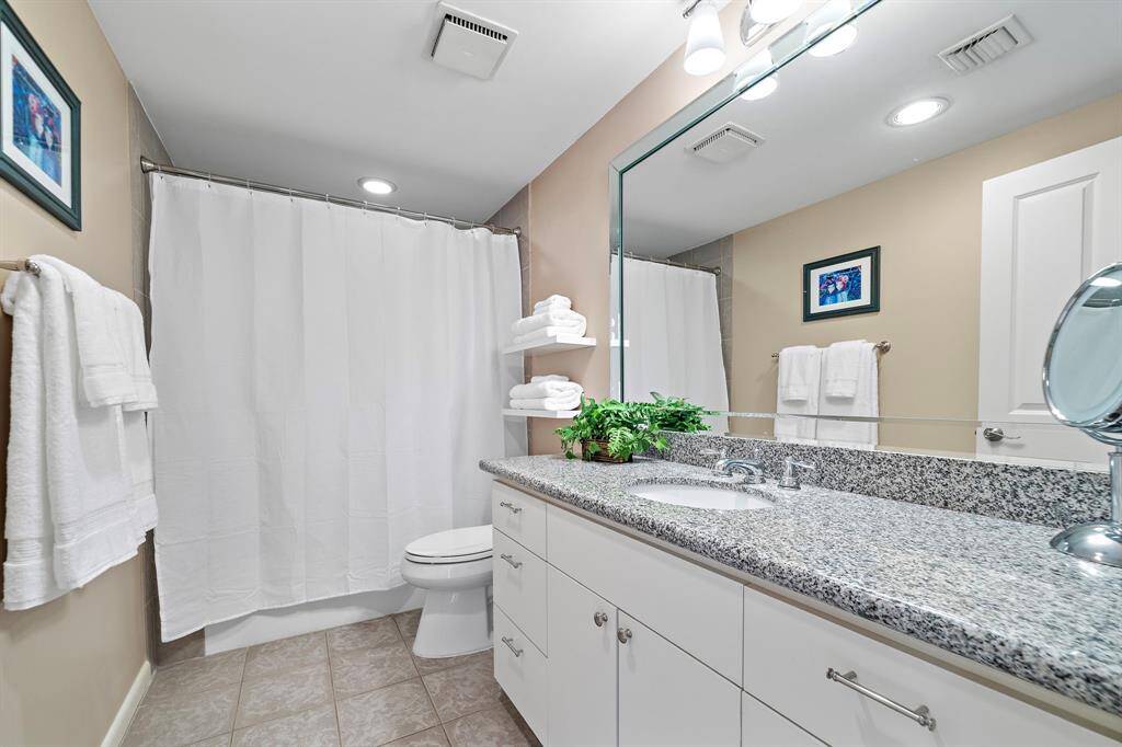 The secondary bathroom is fitted with a combination tub and shower, additional shelves, plus a spacious granite vanity area.
