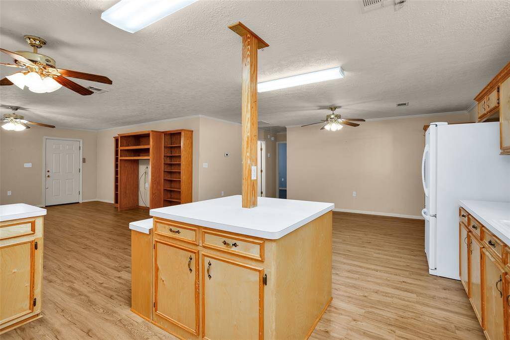 This spacious kitchen features a functional island with built-in electrical outlets and ample storage, perfect for modern living.