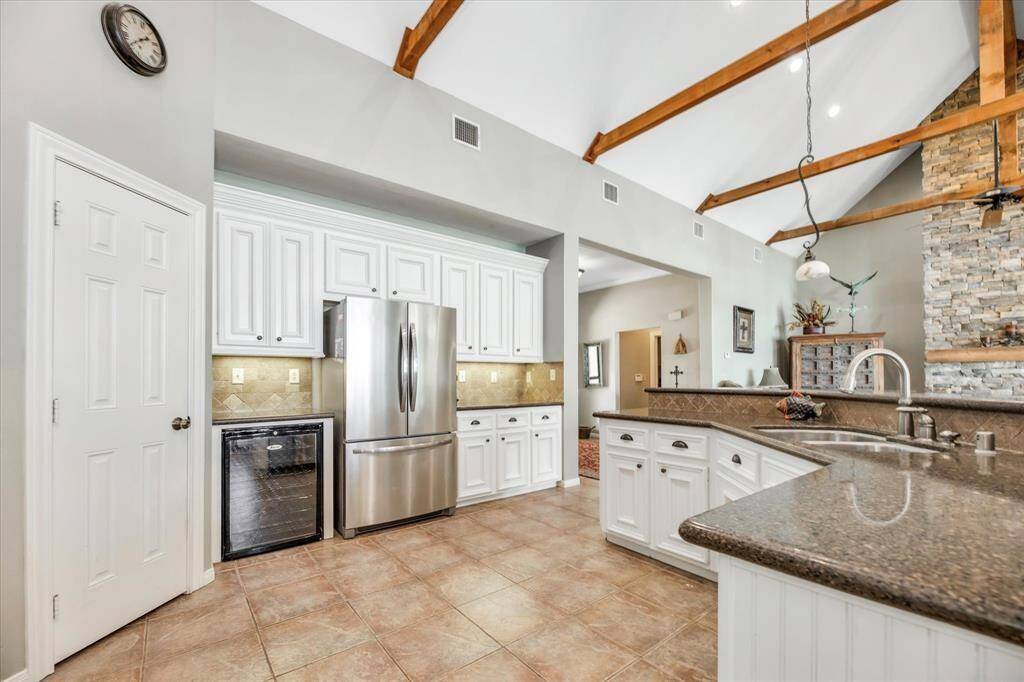 This open concept kitchen features a wine cooler, 5 burner gas cooktop, double oven, walk-in pantry and under cabinet lighting.