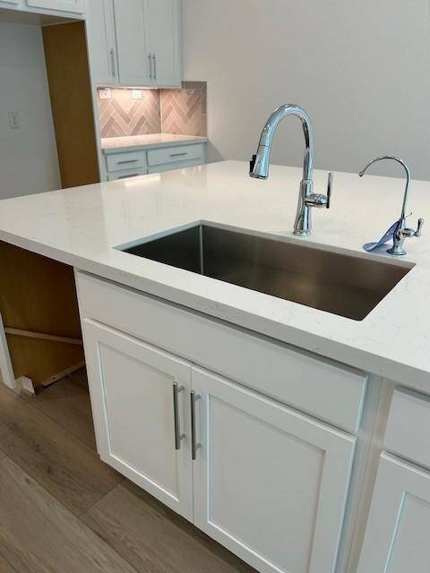 Upgrade counters and sink for a clean modern look. Coffee bar with under cabinet lighting in the background.