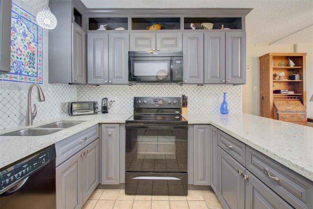 Modern, sleek, and contemporary kitchen with a beautiful tile mural. It has Maytag appliances, granite countertops, and plenty of storage space.