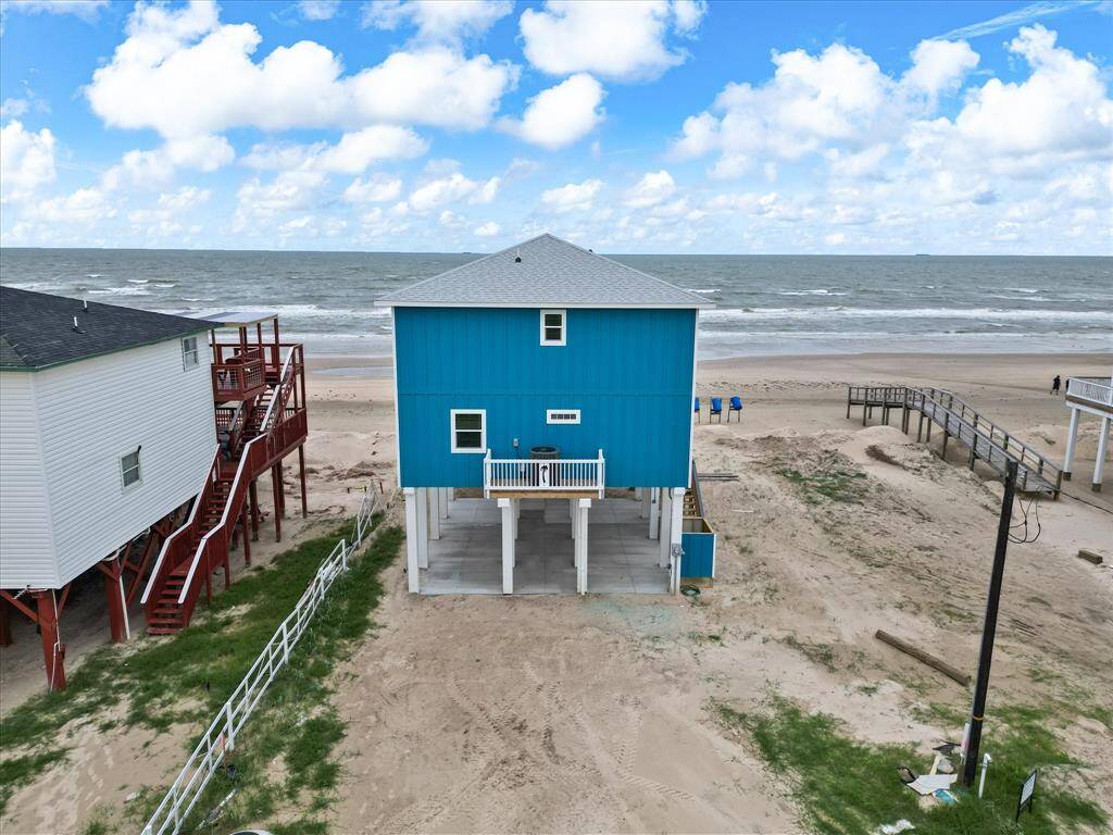 This beachfront home features a vibrant blue exterior with elevated design for ocean views. It offers direct beach access, ideal for seaside living.