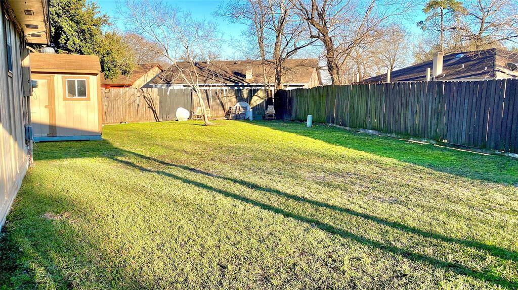 This photo showcases a spacious backyard with well-maintained grass, a wooden fence for privacy, and a small shed. It's an ideal outdoor space for activities and relaxation.