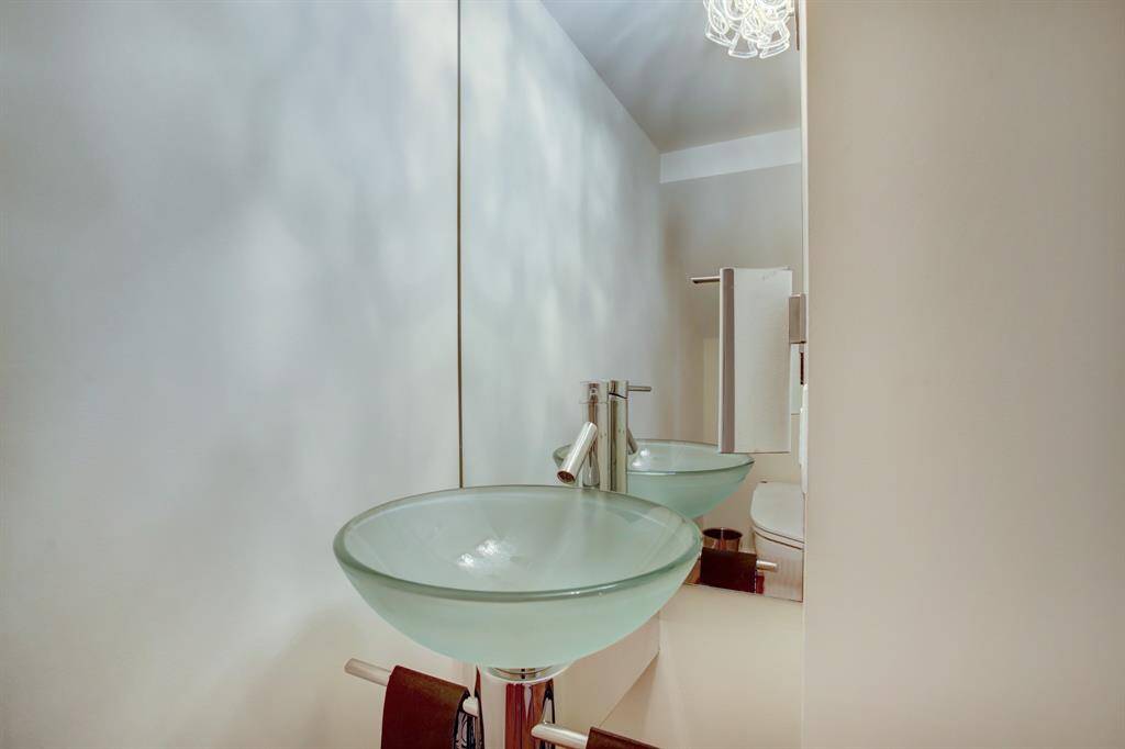 Tucked into the space under the stairway you will find these precious retreat powder room with the artistic addition of this Chromotherapy color change clear glass sink and TOTO Neorest 500 toilet.