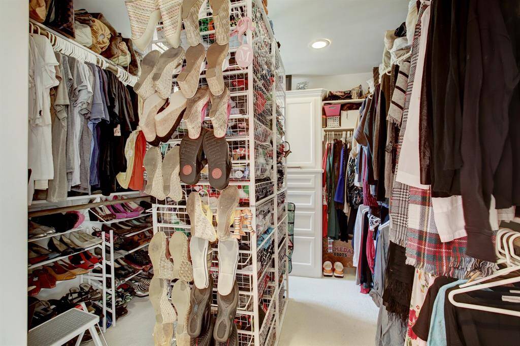This closet is located as you enter the Primary bedroom in the hallway and the owner has added her own "island" style storage piece to add to the already ample storage.  There are built ins with dust cover cabinets here as well as you can see in the rear.