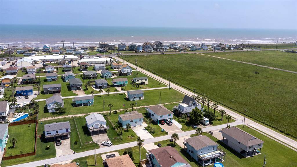 Aerial view of a coastal neighborhood with charming homes, lush green lawns, and proximity to the beach. Ideal for buyers seeking a serene seaside lifestyle.
