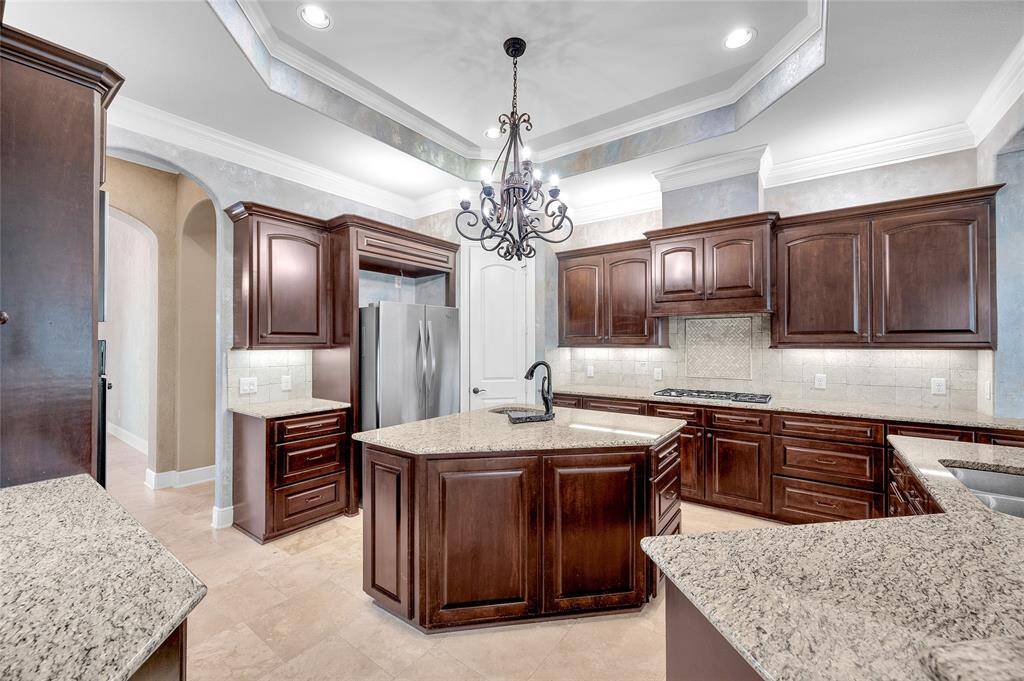 A beautiful chandelier draws your attention to the custom cabinetry which features ambient lighting both below and above the upper cabinets.