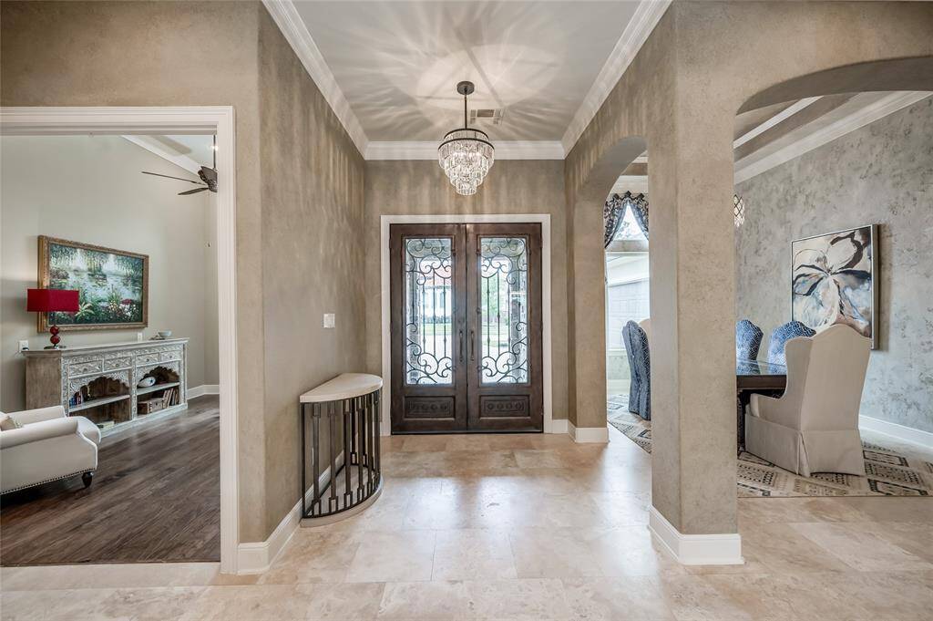 Beautiful iron double doors feature operable glass panels and open into the foyer with a glow of ambient light above.