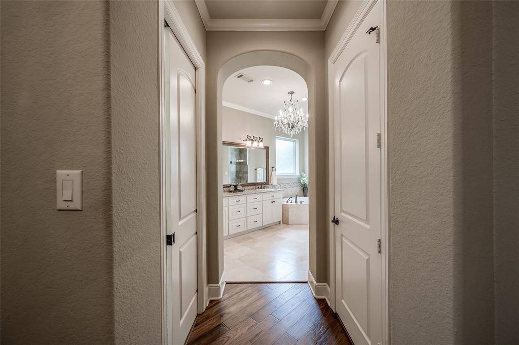 An impressive closet offering a boutique-like experience with custom built-in shelving, drawers and other luxury amenities is through the left door. The right door is a spacious walk-in linen closet.