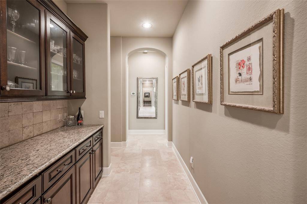 The wine bar is tucked just behind the kitchen and close to the dining room. At the end of the arched hallway are additional bedrooms and bath.