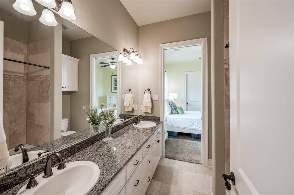 Spacious bathroom with dual sinks and ample storage connects bedroom 2 and bedroom 3.