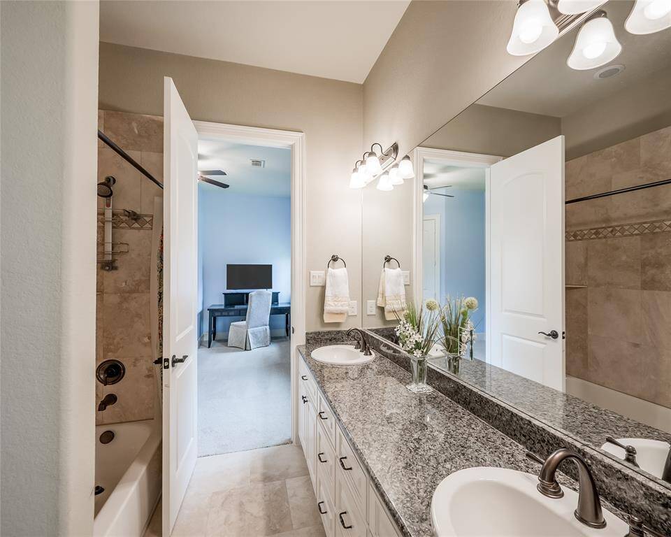 Honed travertine stone and granite counters add natural character to the bathroom shared by bedroom 2 and bedroom 3.