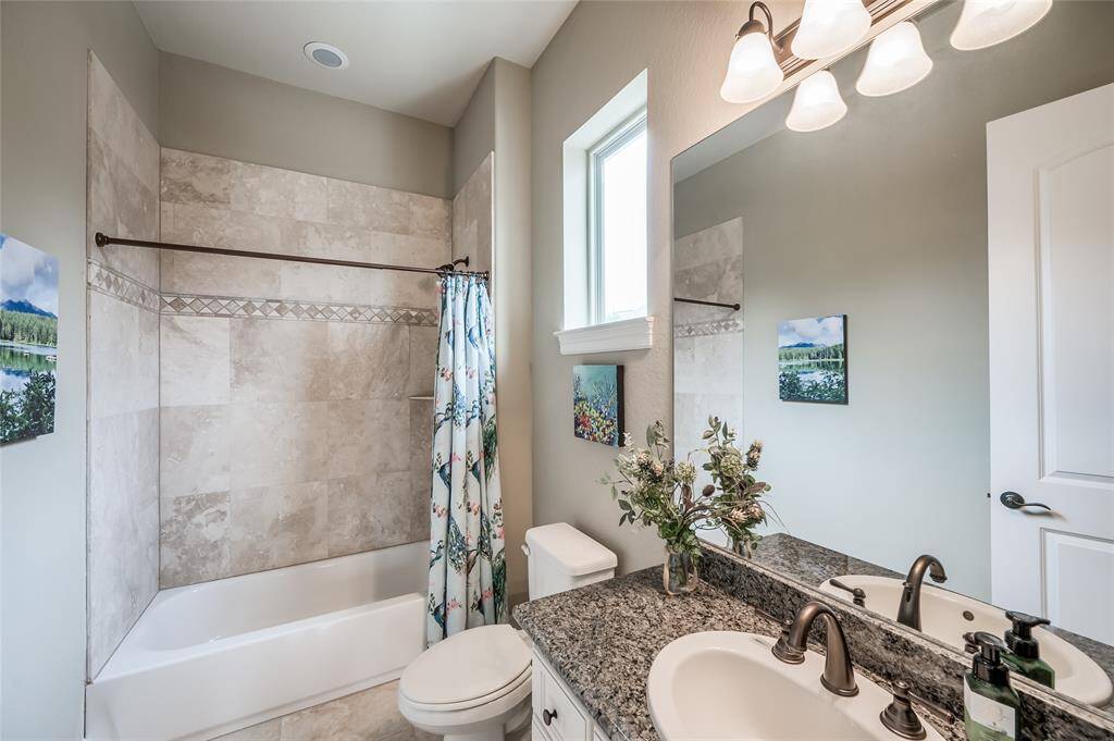 The bathroom for bedroom 4 features honed travertine stone surround and granite counters.  It is also conveniently accessible from the family room.