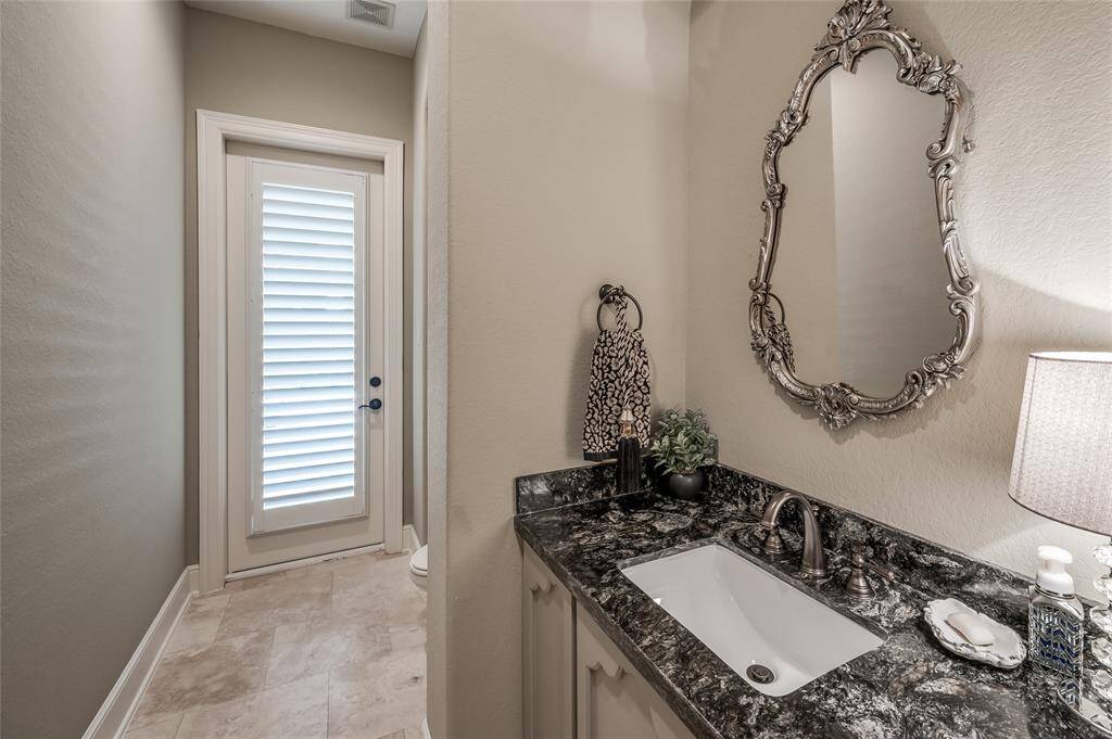 A luxurious powder bath offers enhanced custom details. It is located across from the study and provides a door to the backyard.