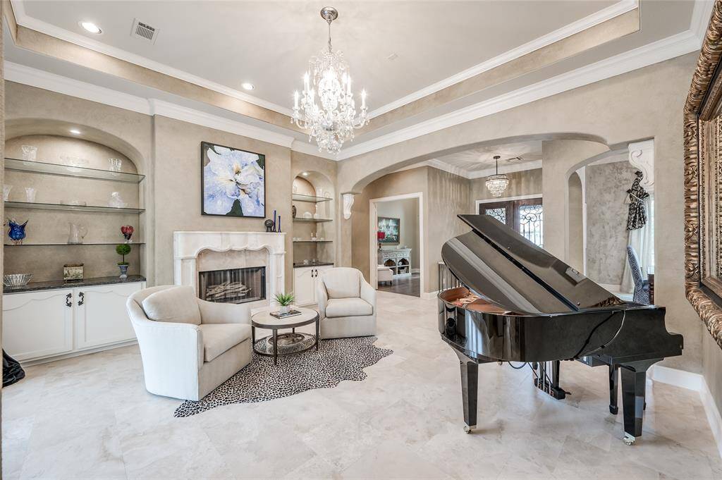 Elegant formal living area that is spacious enough to accommodate a baby grand piano and an inviting seating area, perfect for cocktails. A beautiful stone fireplace adds warmth.