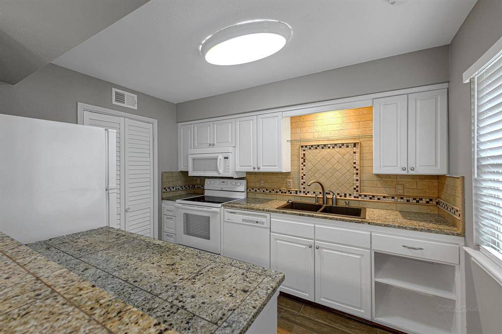 Spacious kitchen with granite countertops and beautiful tile insets