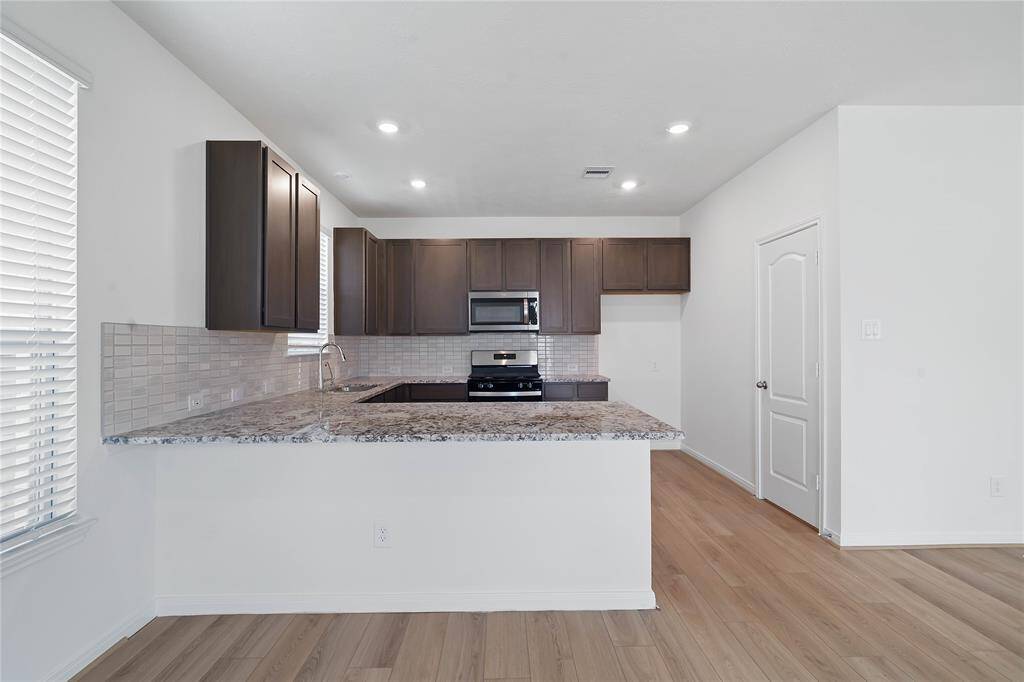 This kitchen is by far any chef’s dream! This spacious kitchen features high ceilings, wood stained cabinets, granite countertops, SS appliances, modern tile backsplash, recessed lighting, extended counter space for breakfast bar, and a walk-in pantry all overlooking your huge family room.
