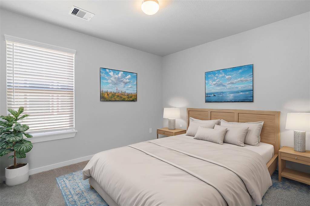 Secondary bedroom features plush carpet, neutral paint and a large window with privacy blinds.
