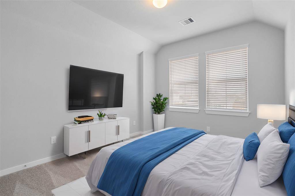 Secondary bedroom features plush carpet, neutral paint and a large window with privacy blinds.