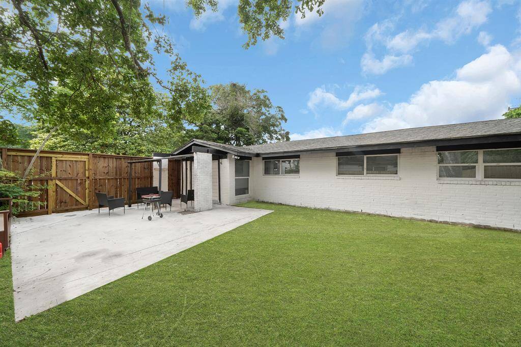 Discover your perfect suburban retreat with a lush lawn, spacious concrete patio, stylish outdoor furniture, and a barbecue grill. This charming white brick home features large windows, inviting natural light and views of the serene backyard.