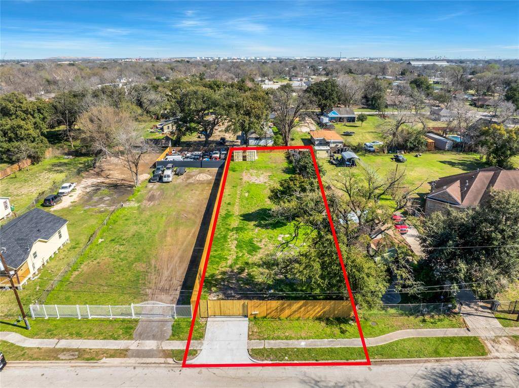 Undeveloped large residential lot outlined in red. It includes a driveway entrance and is ready for construction.