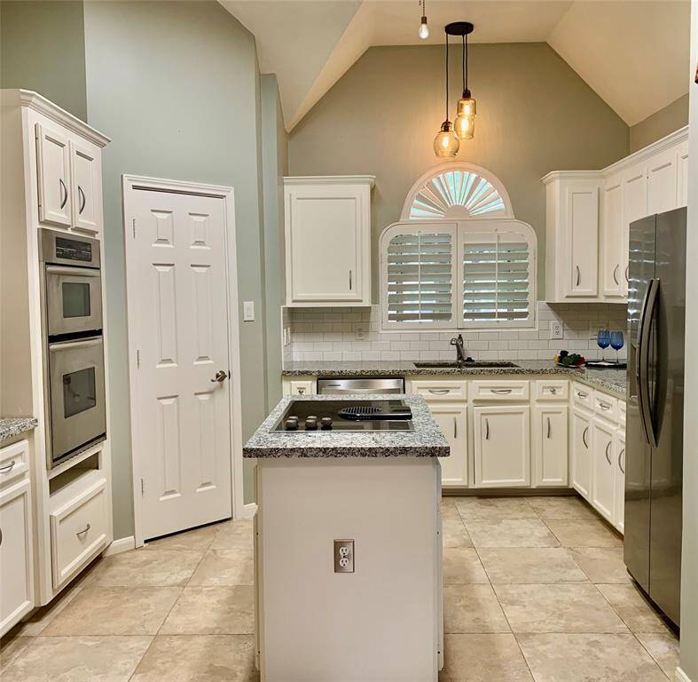 UPDATED KITCHEN WITH GRANITE COUNTERTOPS, SS APPLIANCES, WALK-IN PANTRY, ISLAND COOKTOP, RECENT LIGHTING,AND PLANTATIONS SHUTTERS.