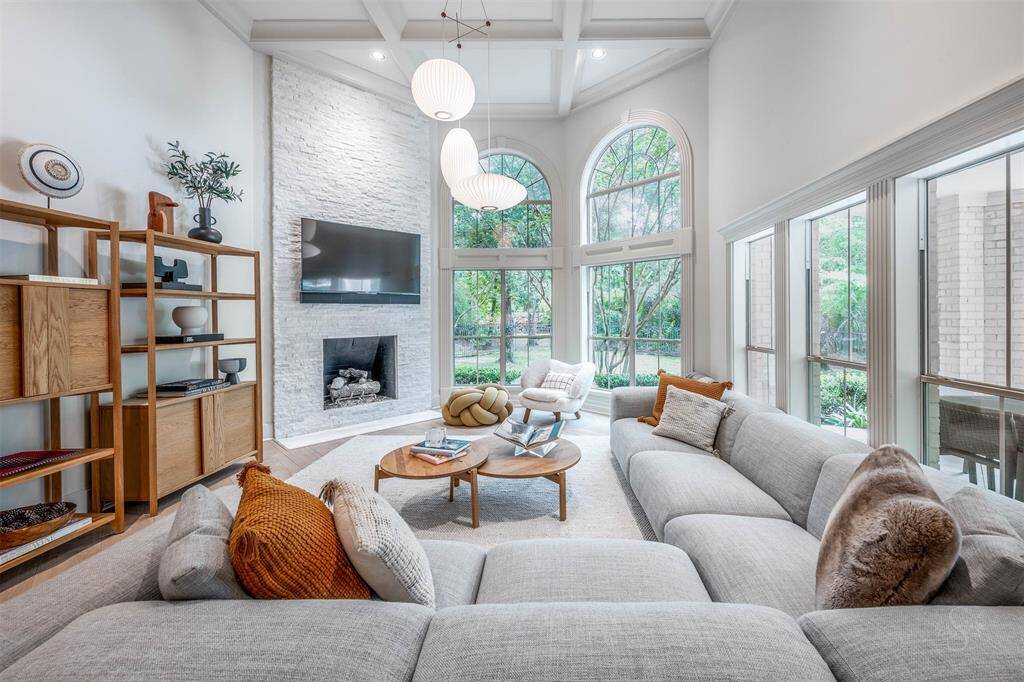 Find a 14ft coffered ceiling, floor to ceiling white stone fireplace and stylish lighting features.