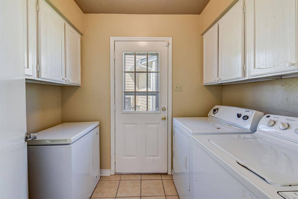 Efficient utility room with ample storage, chest freezer, washer and dryer, and convenient outdoor access.
