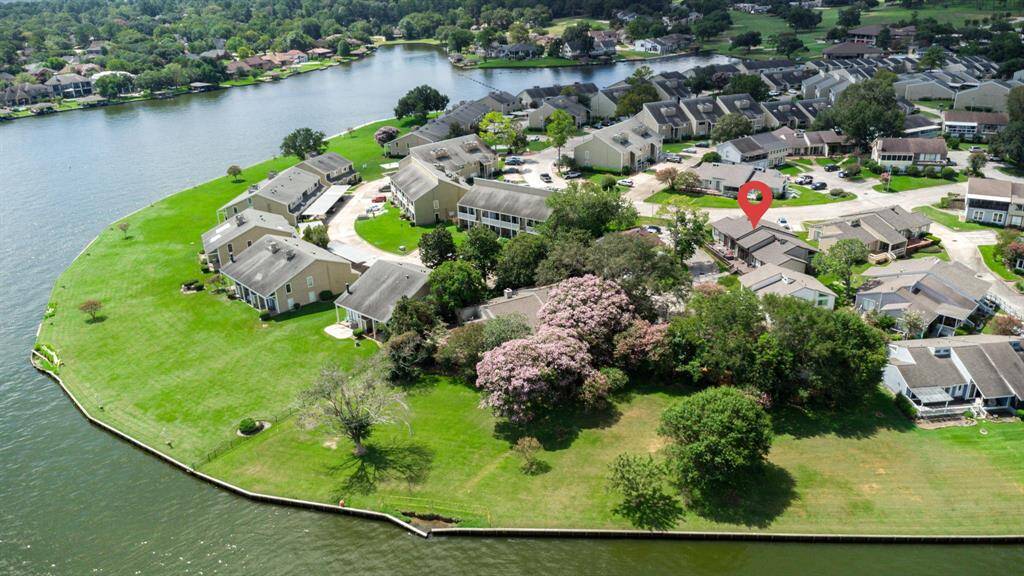 This aerial photo showcases a serene lakeside community with charming homes nestled along the water's edge. The lush greenery and well-maintained lawns add to the tranquil setting, and the location offers beautiful water views and ample outdoor space.