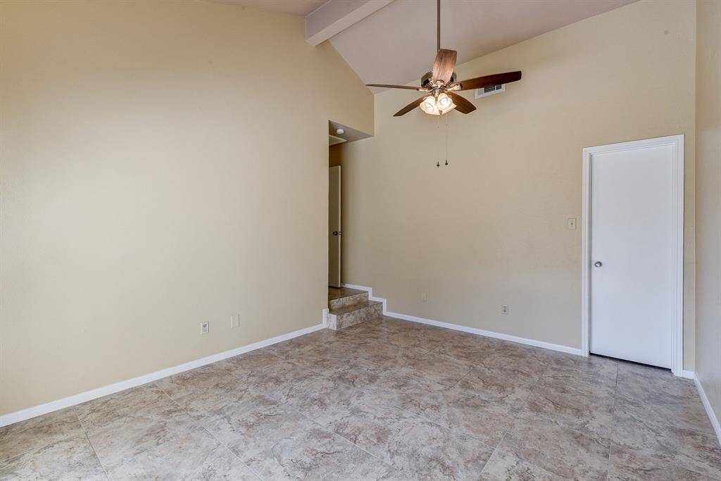Spacious corner bedroom with high ceilings, tile flooring, and a ceiling fan. Perfect for comfort and style.