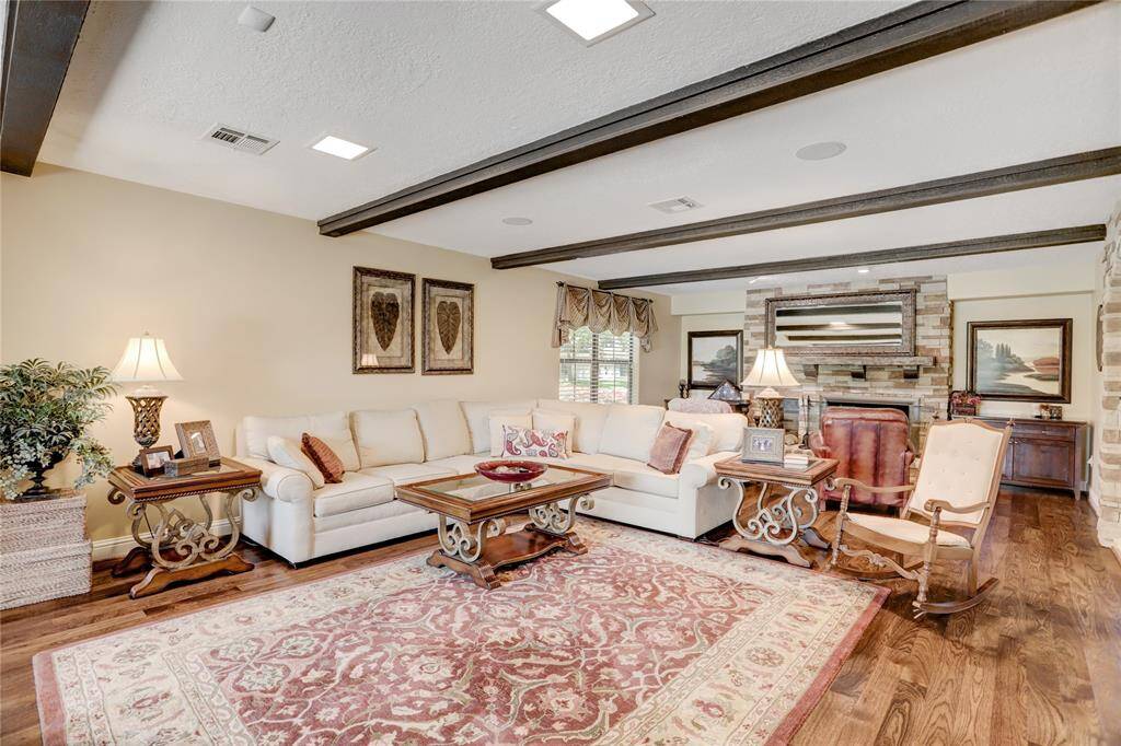 The expansive living room has gleaming wood floors and ample room for furnishings centered on the fireplace and the windows overlooking the lake.