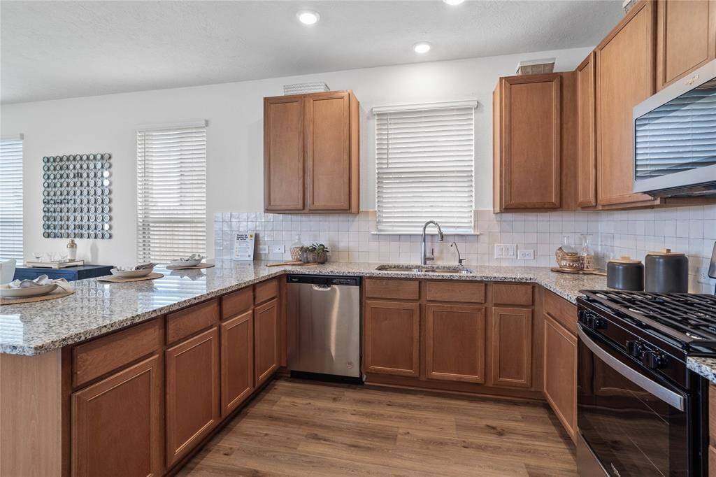 Additional picture of the kitchen featuring the stainless steel appliances, modern tile backsplash, and gorgeous granite countertops.