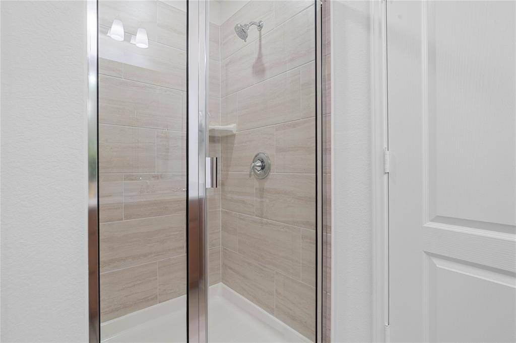 Additional view of the primary bathroom featuring a walk-in shower with tile surround, high ceilings, custom paint, sleek and dark modern finishes.